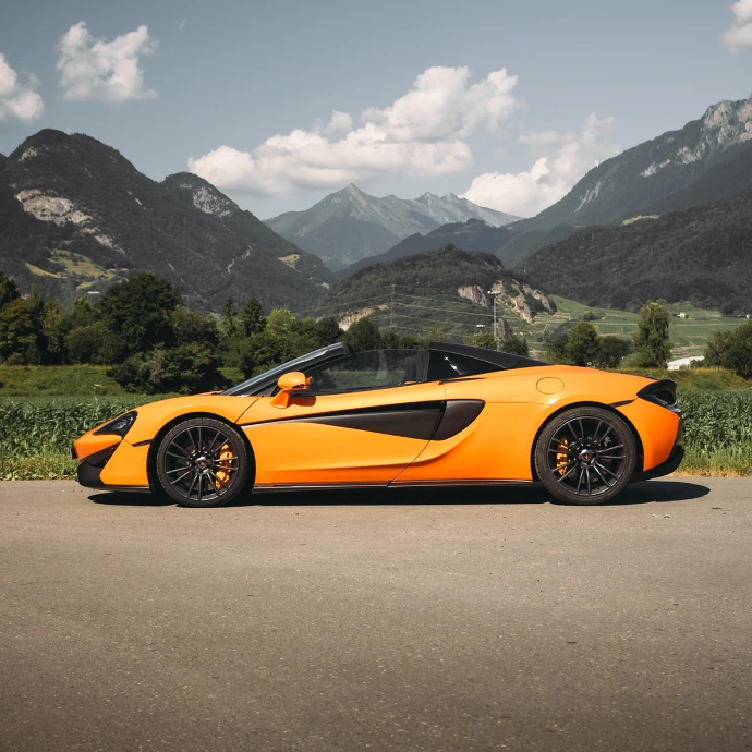 Profil de la McLaren 570S Spider, toit ouvert et jantes sport. Expérience de conduite à ciel ouvert, location en Suisse.