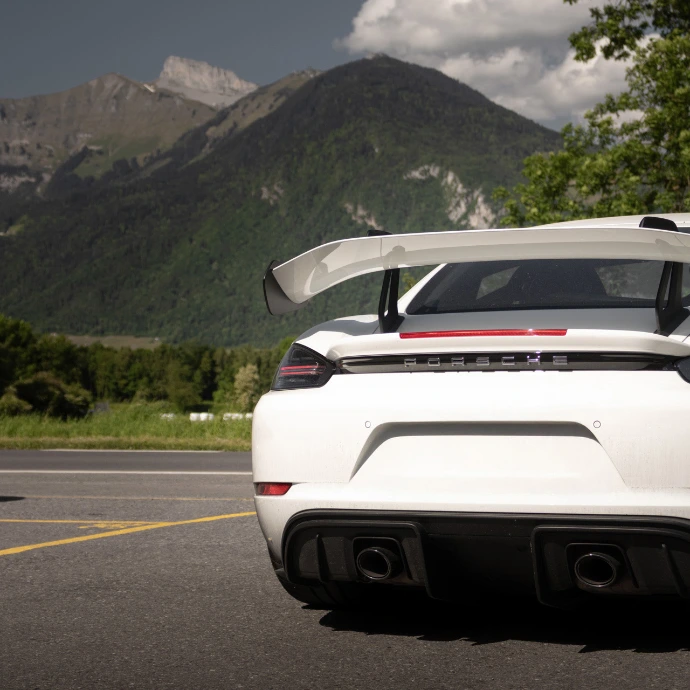 Vue arrière Porsche GT4 RS, aileron fixe et échappement central. Location Porsche hautes performances Suisse.