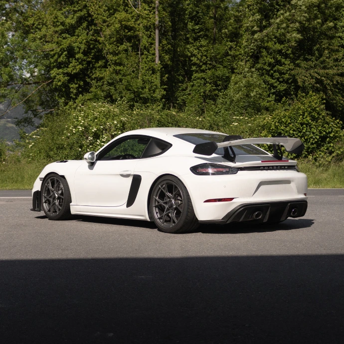 Profil Porsche GT4 RS, châssis bas et lignes agressives. Expérience de conduite sportive disponible à la location en Suisse.