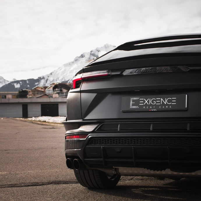 Vue arrière Lamborghini Urus S, signature lumineuse et échappements sport. Location Suisse.